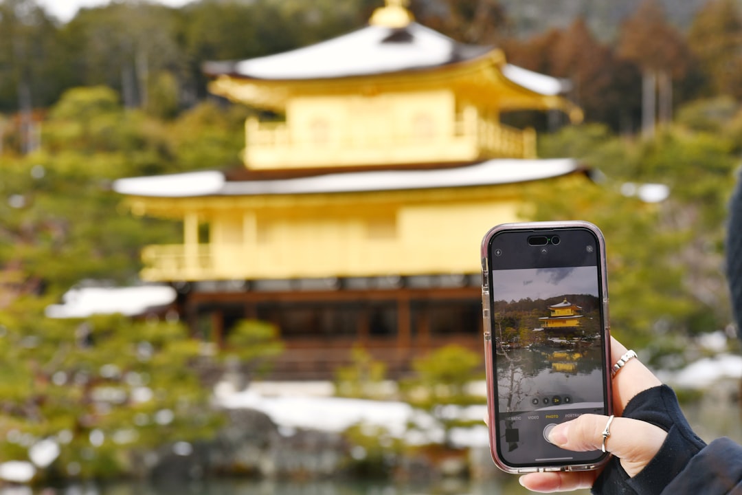 Traveler photographing Kinkaku-ji in Kyoto with a smartphone, used for the guide to booking Japan activities before arrival